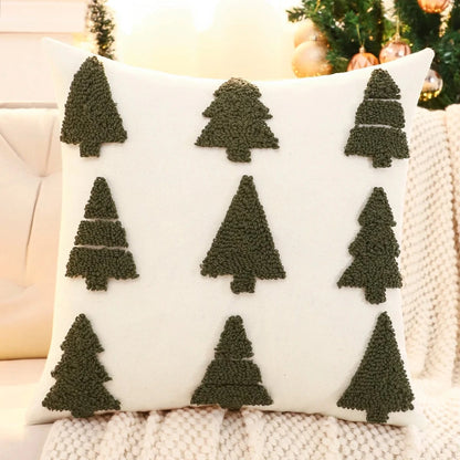Coussin décoratif blanc avec motifs d'arbres de Noël en velours vert, posé sur un canapé cosy