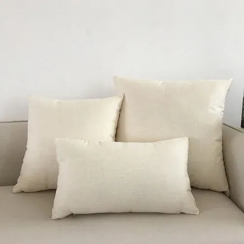 Trois coussins décoratifs beiges aux textures variées, posés sur un canapé clair dans un salon moderne