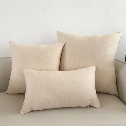 Trois coussins décoratifs beige en tissu texturé, posés sur un canapé clair dans un salon moderne