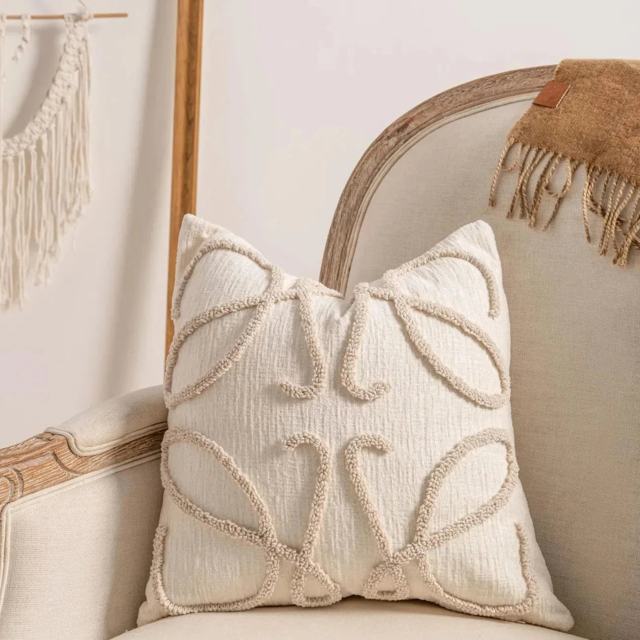 Coussin décoratif en tissu beige avec motifs géométriques, posé sur un fauteuil élégant dans un intérieur moderne