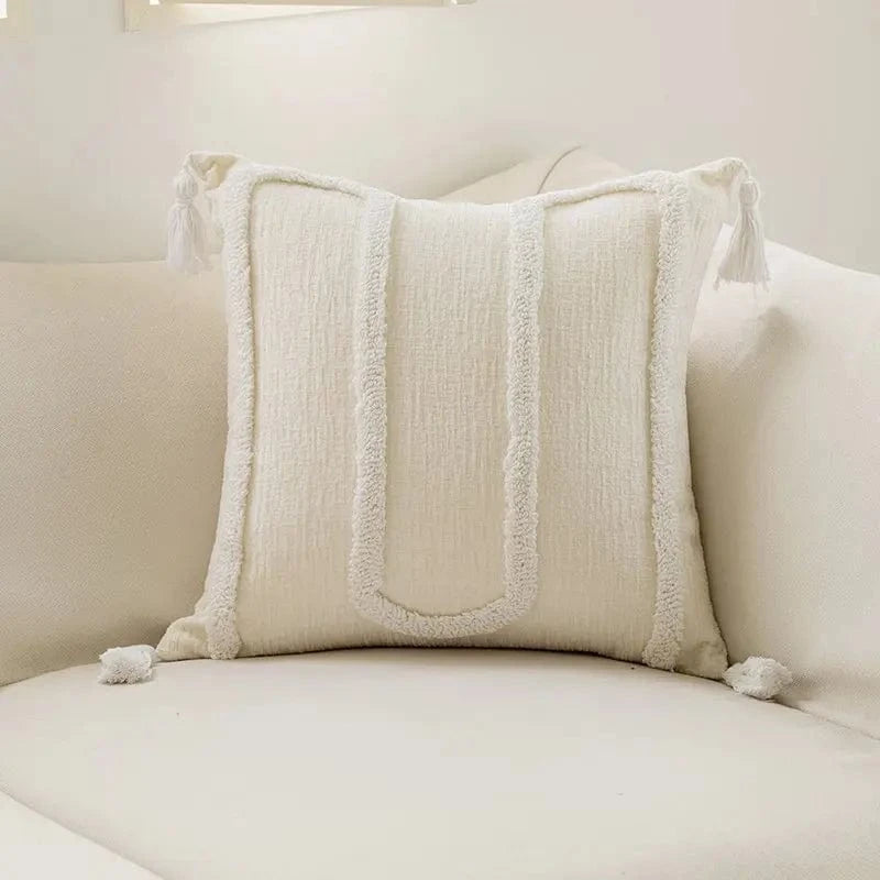 Coussin décoratif blanc en texture douce avec motifs géométriques, posé sur un canapé moderne et élégant
