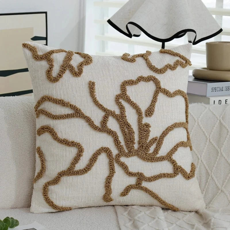 Coussin décoratif beige avec motifs géométriques en relief, posé sur un canapé moderne dans un salon lumineux