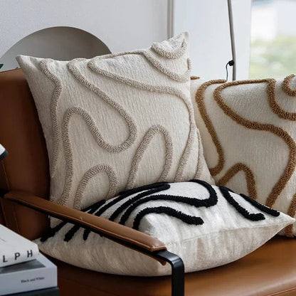 Coussins décoratifs aux motifs géométriques en beige et noir, posés sur un canapé en cuir moderne