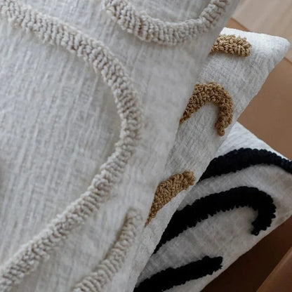 Trois coussins décoratifs aux motifs géométriques en textile raffiné, disposés sur un canapé moderne