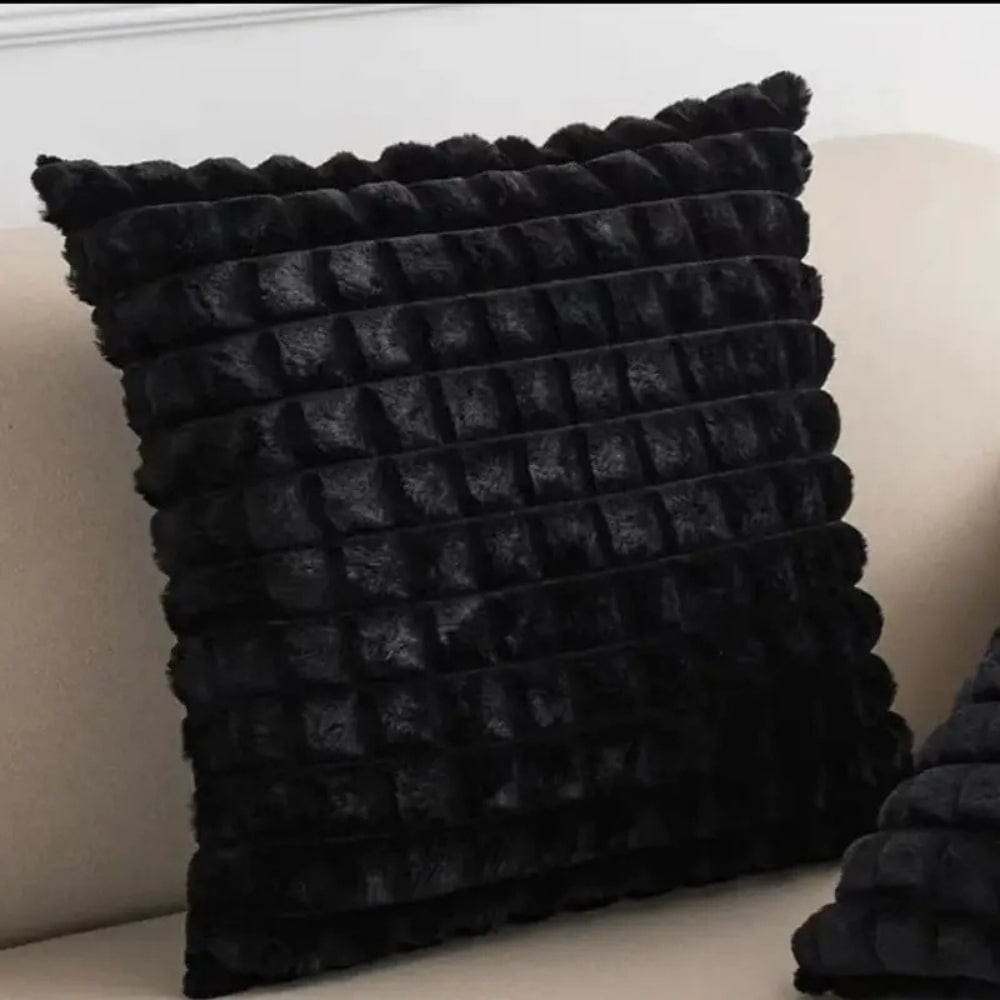 Coussin décoratif noir en velours texturé, posé sur un canapé beige, ajoutant une touche élégante au salon