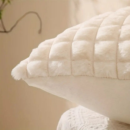Coussin décoratif en velours blanc, avec un motif quadrillé, posé sur un canapé élégant dans un salon lumineux