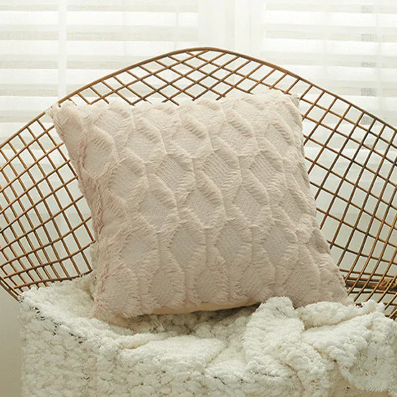 Coussin décoratif en velours rose avec motif texturé, posé sur un canapé en tissu blanc dans un salon lumineux