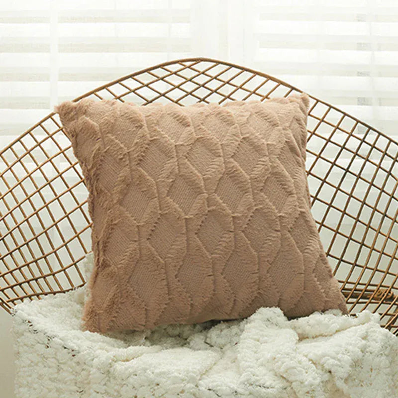 Coussin décoratif en velours beige avec motif en relief, placé sur un fauteuil en métal dans un salon lumineux