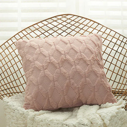 Coussin décoratif rose avec un motif texturé, posé sur un fauteuil en rotin dans un salon lumineux
