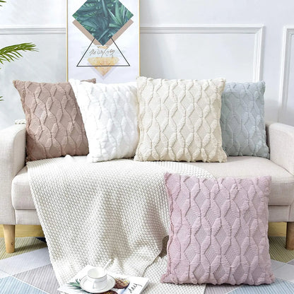 Coussins décoratifs aux teintes douces, en matière texturée, disposés sur un canapé avec un plaid