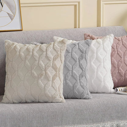 Coussins décoratifs aux couleurs neutres et motifs géométriques, posés sur un canapé gris doux