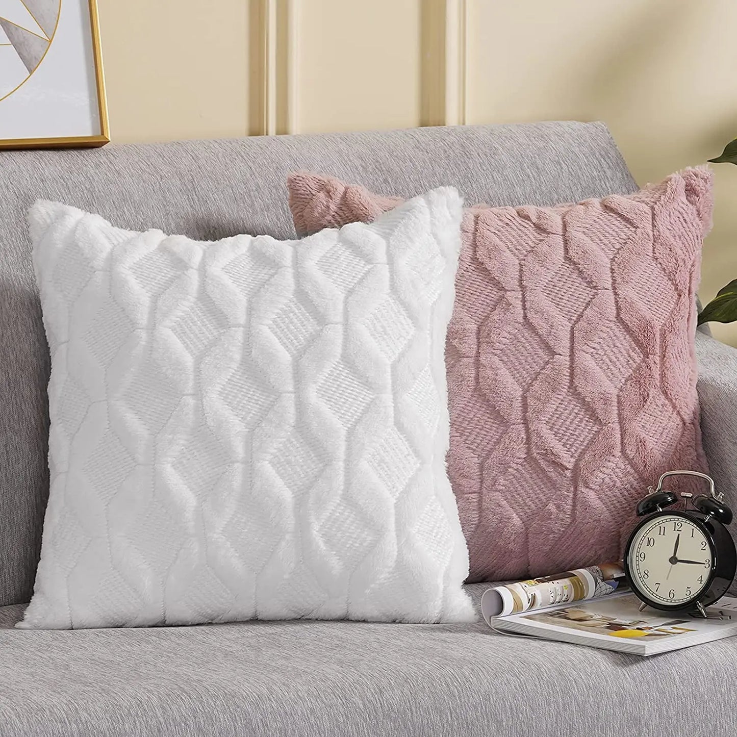 Coussins décoratifs en velours blanc et rose, à motifs géométriques, posés sur un canapé gris