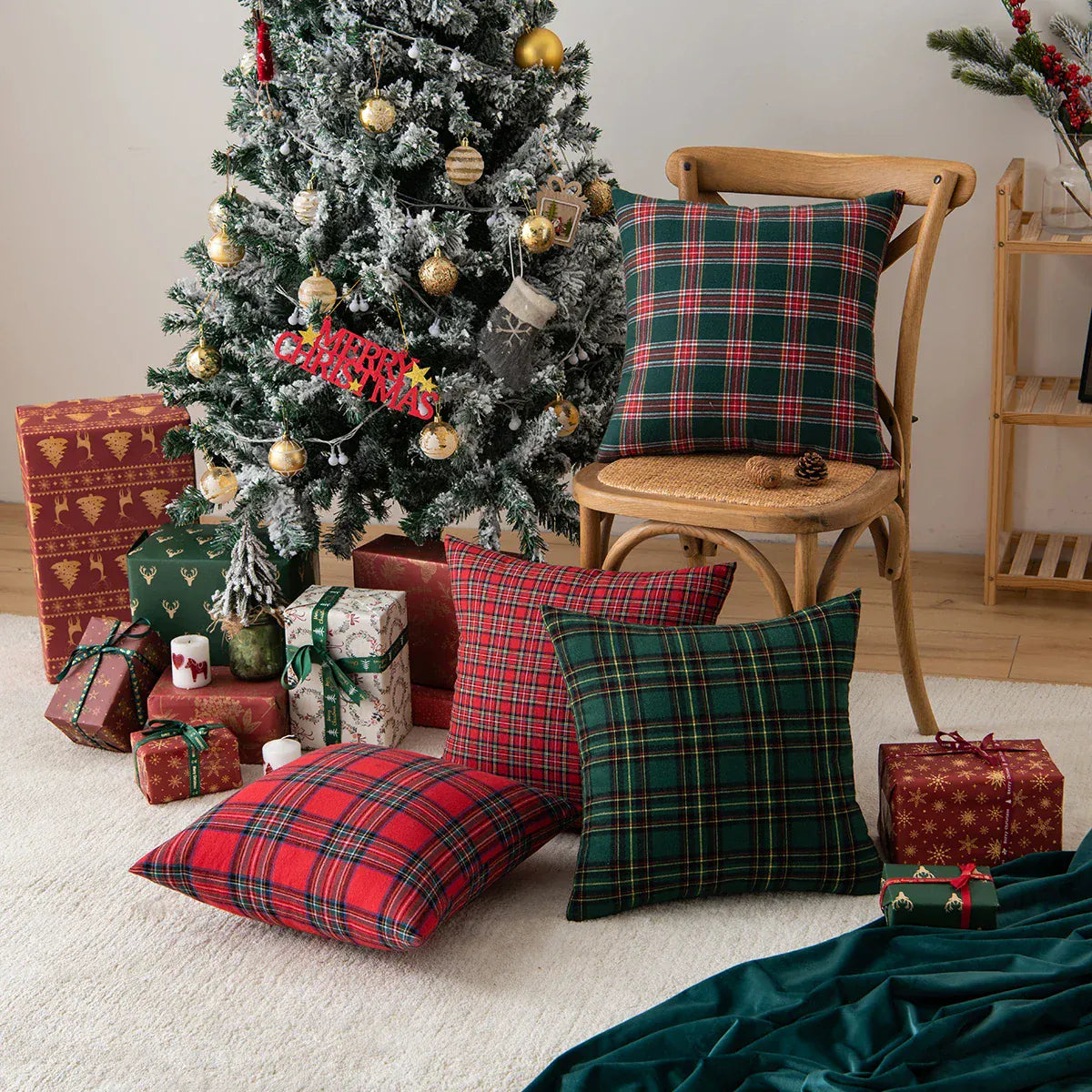 Coussins décoratifs à motifs écossais rouge et vert, disposés sur une chaise en bois près d'un sapin de Noël