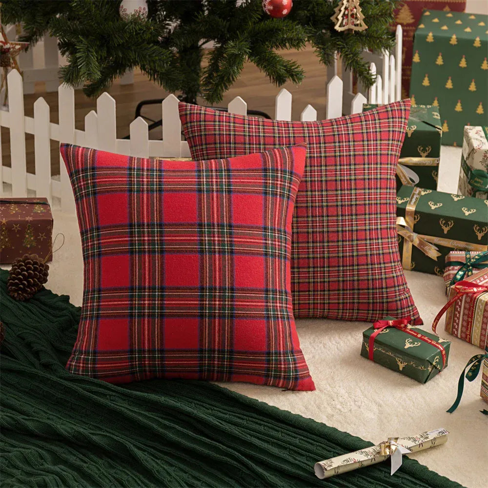 Coussins décoratifs en tissu écossais rouge et noir, posés sur un tapis vert près d'un sapin de Noël