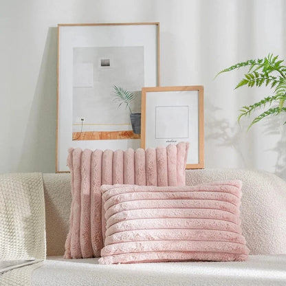 Coussins décoratifs en fausse fourrure rose, posés sur un canapé beige, ajoutant une touche cocooning au salon