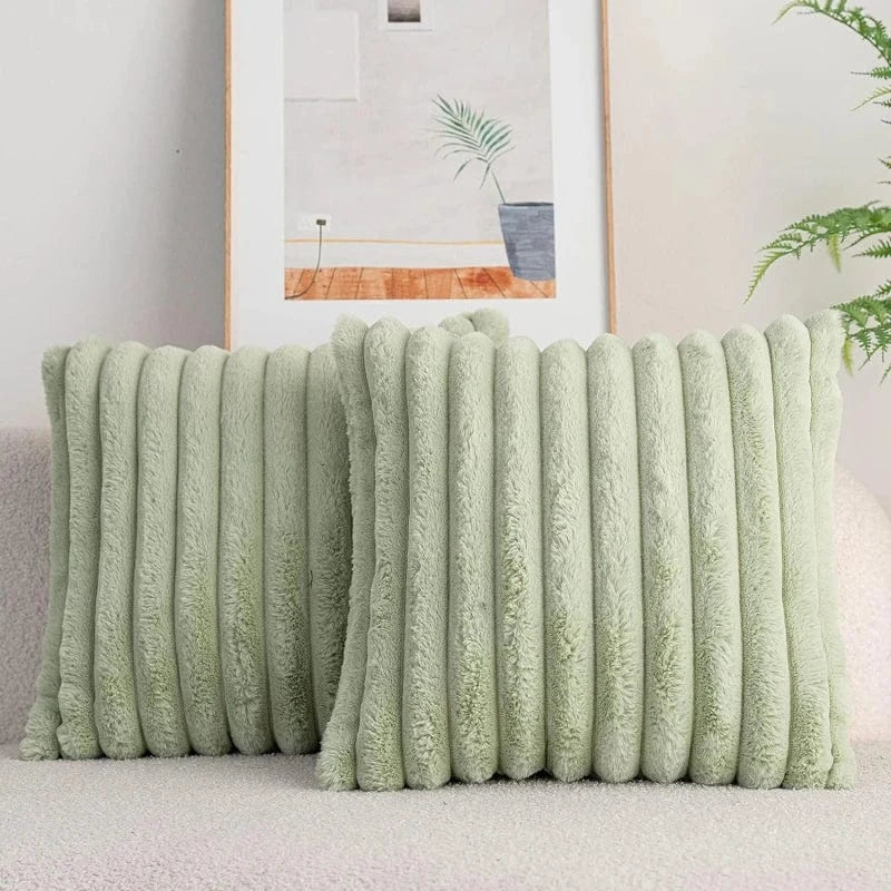 Coussins décoratifs en fausse fourrure verte, posés sur un canapé doux, ajoutant une touche cocooning à la décoration intérieure