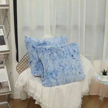 Deux coussins décoratifs en fausse fourrure bleu, posés sur un canapé blanc, ajoutent une touche de confort