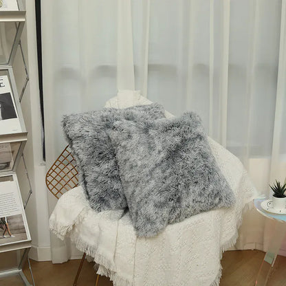 Deux coussins en fausse fourrure grise posés sur un fauteuil, décorant un coin de salon chaleureux