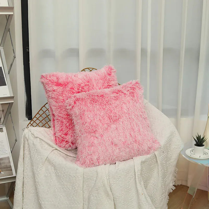 Deux coussins décoratifs en fausse fourrure rose posés sur un canapé blanc dans un salon lumineux