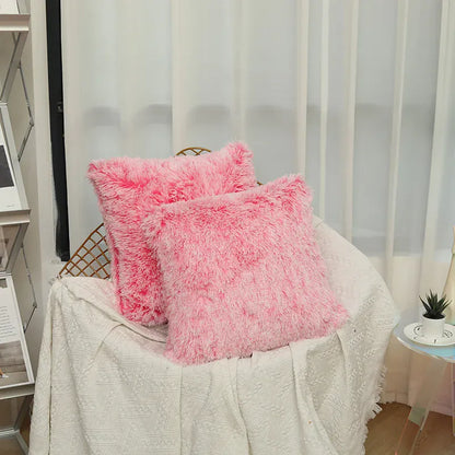 Deux coussins décoratifs en fausse fourrure rose posés sur un canapé blanc dans un salon lumineux