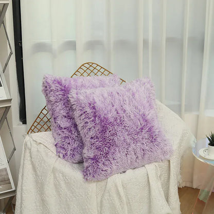 Deux coussins en fausse fourrure violette posés sur un canapé blanc dans un salon lumineux
