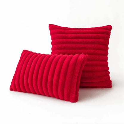 Deux coussins décoratifs en fourrure rouge, l'un carré et l'autre rectangulaire, posés sur un fond blanc