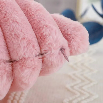 Housse de coussin en fourrure rose sur une surface douce, ajoutant une touche chaleureuse à votre décor