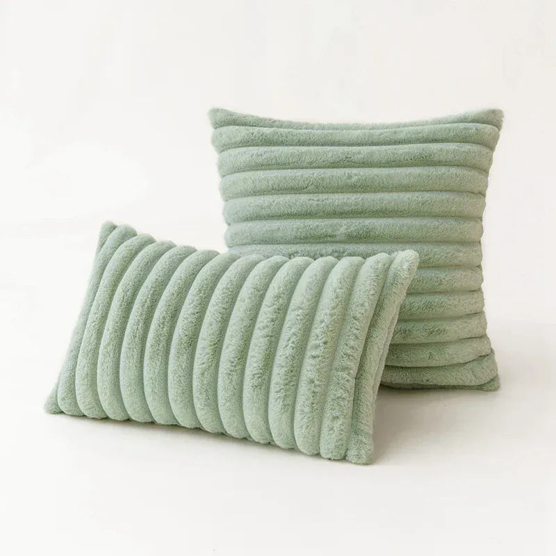 Coussins décoratifs en fourrure vert pastel, à rayures, posés sur un canapé moderne dans un salon élégant