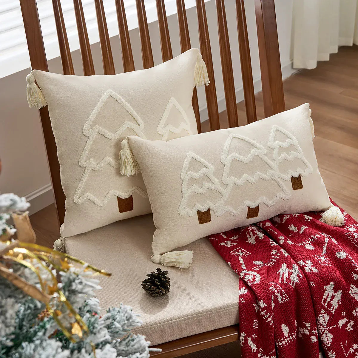 Coussins décoratifs en lin beige avec motifs d'arbres, posés sur une chaise en bois dans un salon chaleureux