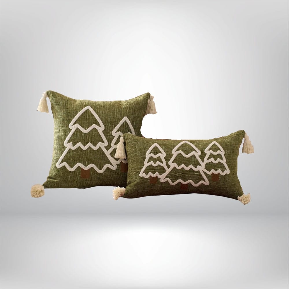 Coussins décoratifs en lin vert avec motifs d'arbres blancs et pompons, posés sur un fond neutre