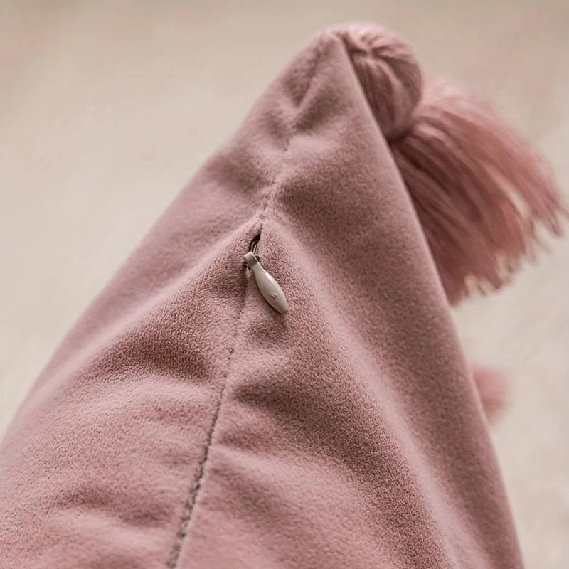 Housse de coussin en velours rose avec un pompon, idéale pour un décor bohème sur un canapé