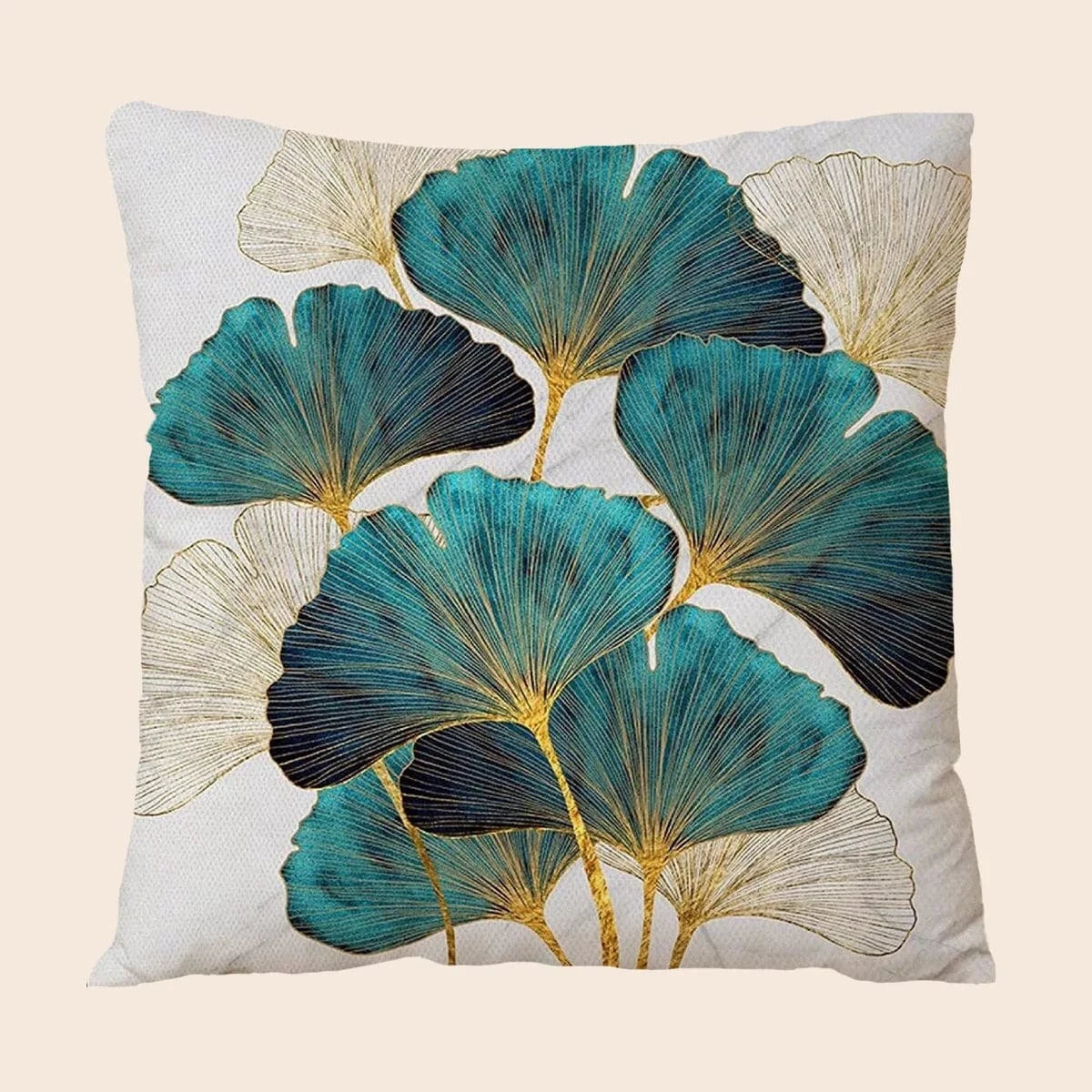 Coussin décoratif aux motifs de feuilles turquoise et dorées sur fond clair, posé sur un canapé moderne