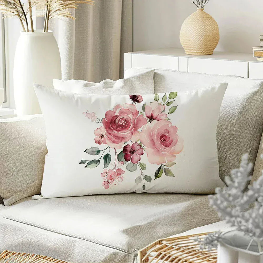 Coussin décoratif blanc avec motif floral rose, posé sur un canapé beige dans un salon lumineux