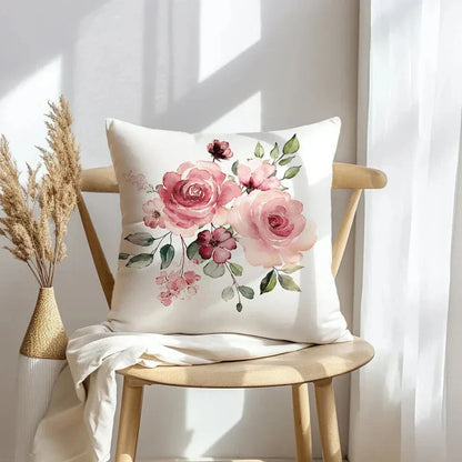 Housse de coussin décorative avec des fleurs roses sur fond crème, posée sur une chaise en bois