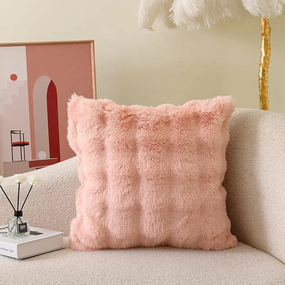 Coussin déco en fourrure rose, posé sur un canapé beige, avec un motif texturé et doux au toucher
