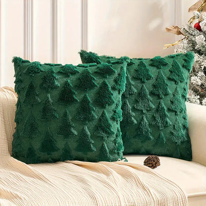 Deux coussins décoratifs verts en velours avec motifs de sapins, posés sur un canapé beige