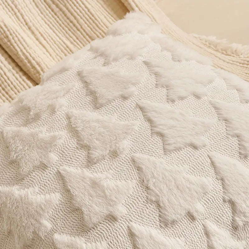 Housse de coussin décoratif en tissu doux avec motifs de sapins blancs sur fond crème, posé sur un canapé