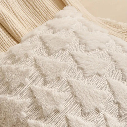 Housse de coussin décoratif en tissu doux avec motifs de sapins blancs sur fond crème, posé sur un canapé