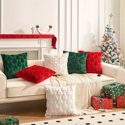 Housse de coussin décorative aux motifs sapins, en velours rouge, vert et blanc, sur un canapé moderne