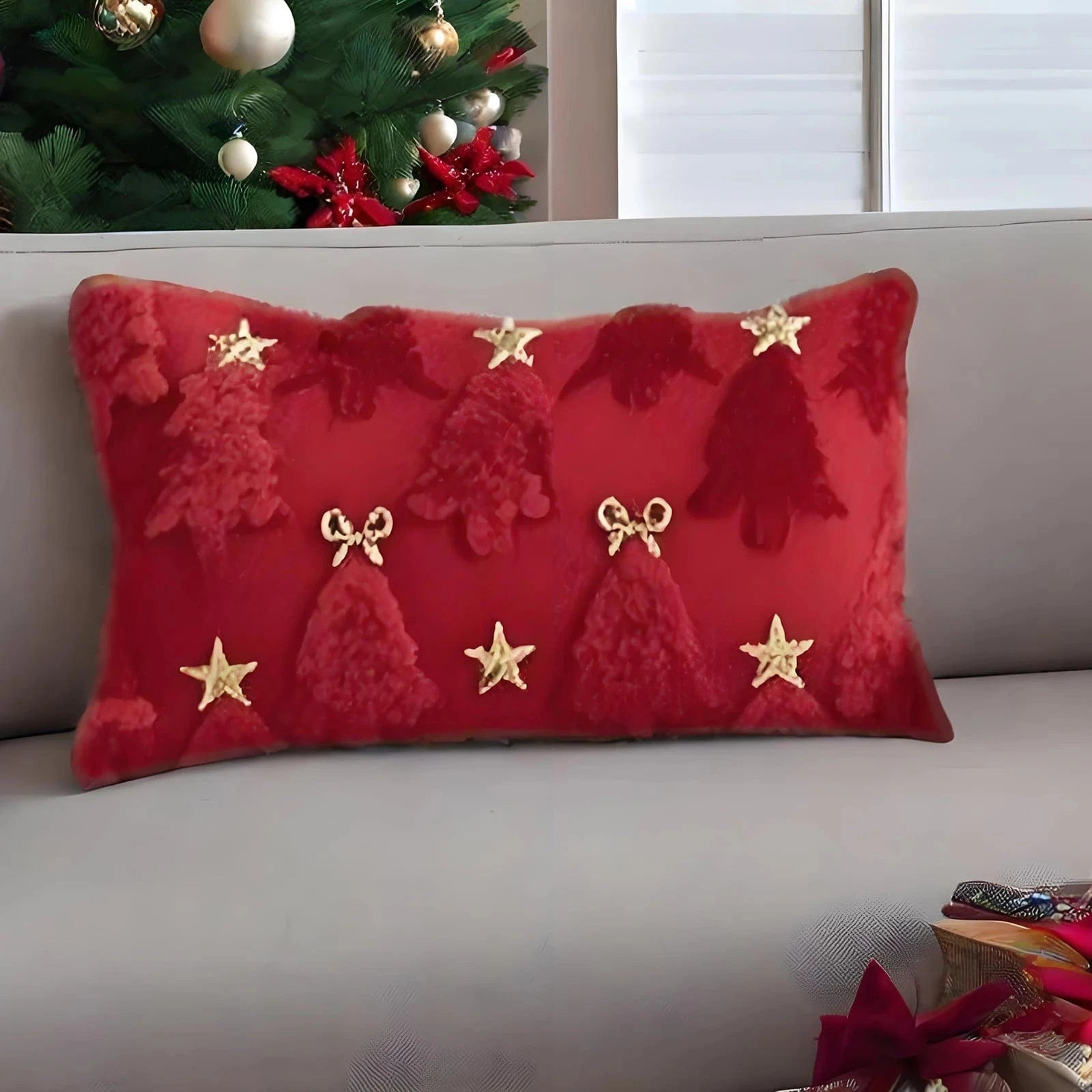 Coussin décoratif rouge avec motifs de sapins et étoiles dorées, posé sur un canapé dans une ambiance festive
