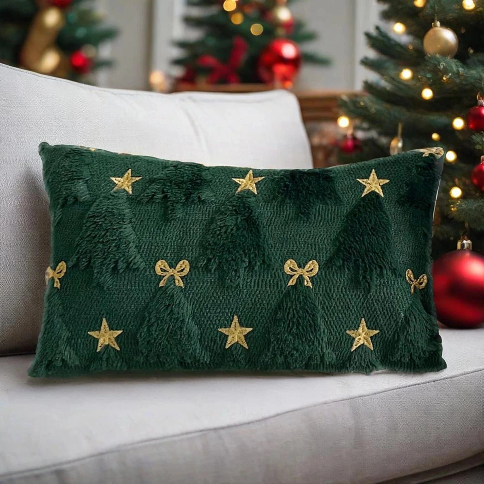 Coussin décoratif vert avec motifs d'arbres et étoiles dorées, posé sur un canapé dans une ambiance festive