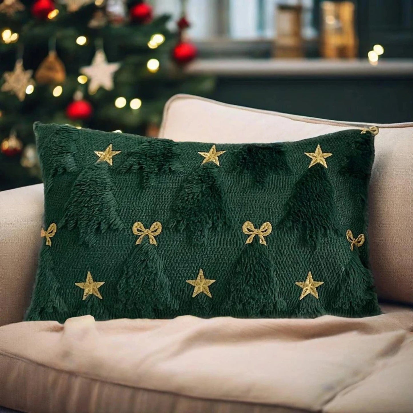 Coussin décoratif vert avec motifs d'arbres de Noël et étoiles dorées, posé sur un canapé beige dans une ambiance festive