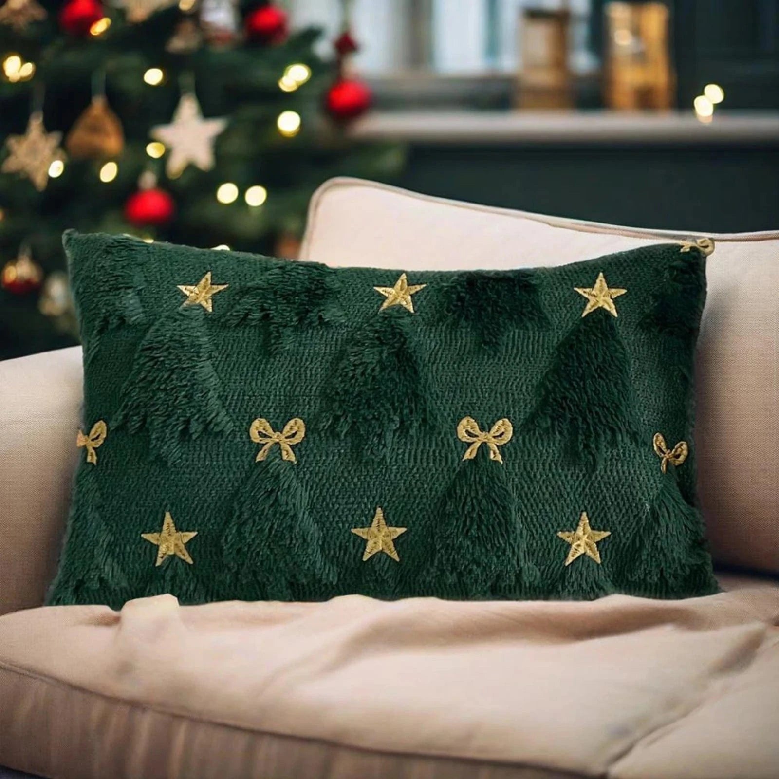 Coussin décoratif vert avec motifs d'arbres de Noël et étoiles dorées, posé sur un canapé beige dans une ambiance festive
