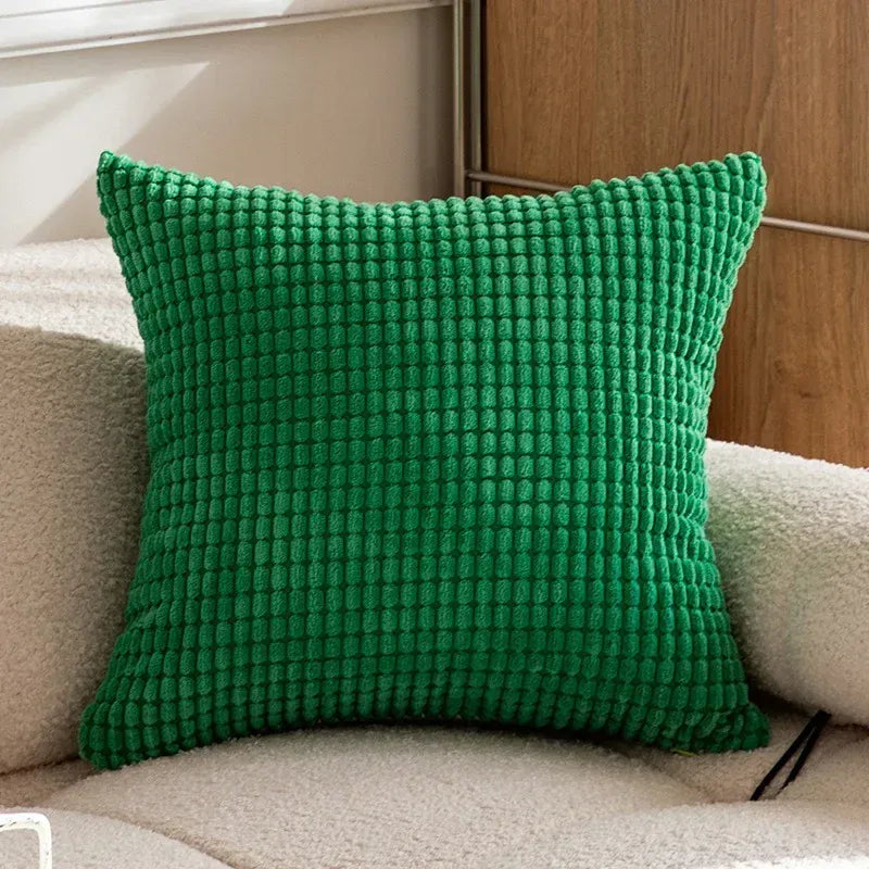 Coussin décoratif vert texturé, posé sur un canapé beige, ajoutant une touche de couleur au salon