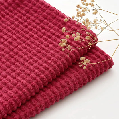 Housse de coussin rouge texturée avec motifs en relief, idéale pour un décor chaleureux dans un salon