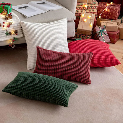 Quatre coussins décoratifs aux textures côtelées, rouge, vert, blanc, disposés sur un tapis dans un salon chaleureux