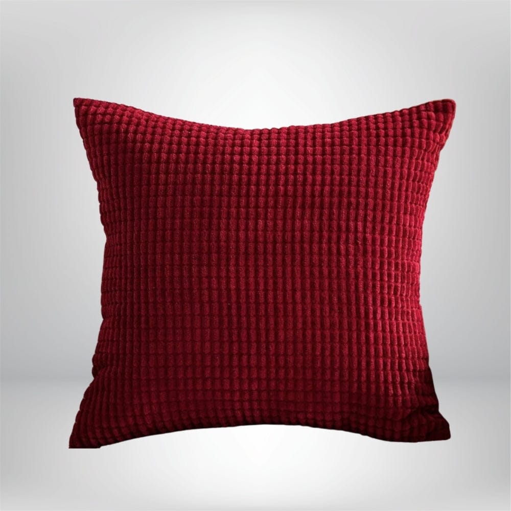Coussin décoratif en velours rouge, texturé, posé sur un fond neutre, idéal pour un canapé ou un lit
