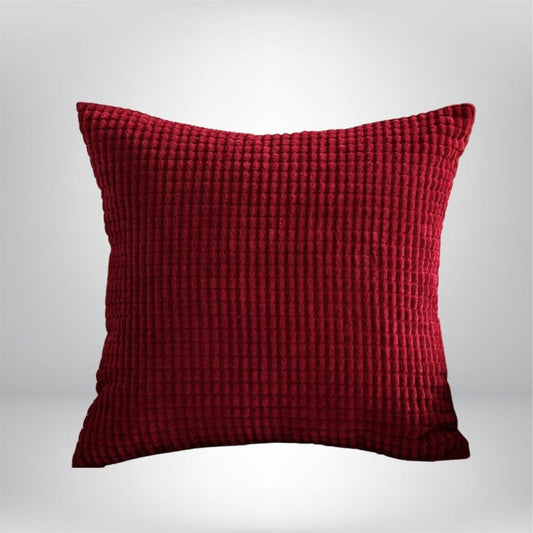 Coussin décoratif en velours rouge, texturé, posé sur un fond neutre, idéal pour un canapé ou un lit