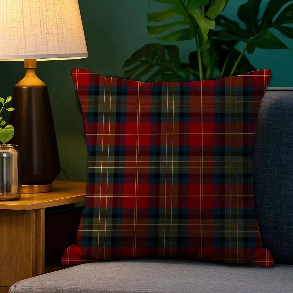 Coussin décoratif à motif tartan rouge et vert, posé sur un canapé dans un salon chaleureux