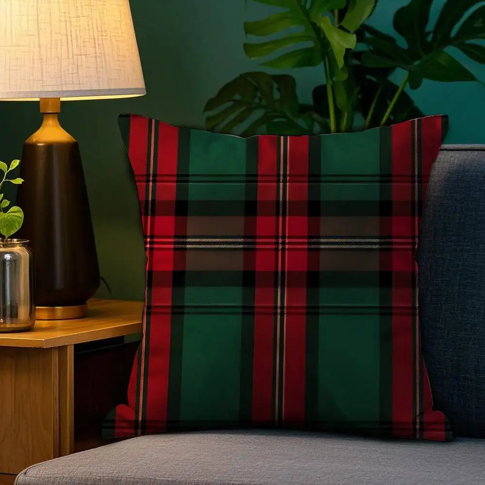 Coussin décoratif à motif tartan rouge et vert posé sur un canapé gris, éclairé par une lampe